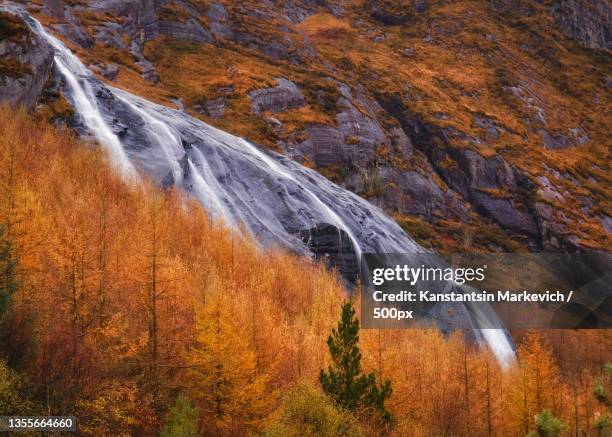 over the fiery larch trees,scenic view of waterfall during autumn,gleninchaquin park,ireland - gleninchaquin stock-fotos und bilder