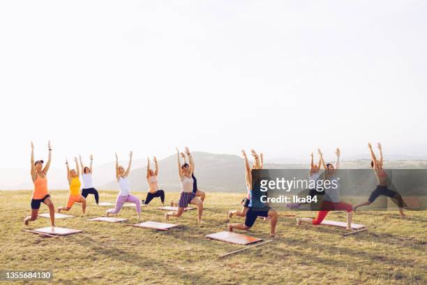 group of women attending yoga class outdoors - yoga group stock pictures, royalty-free photos & images
