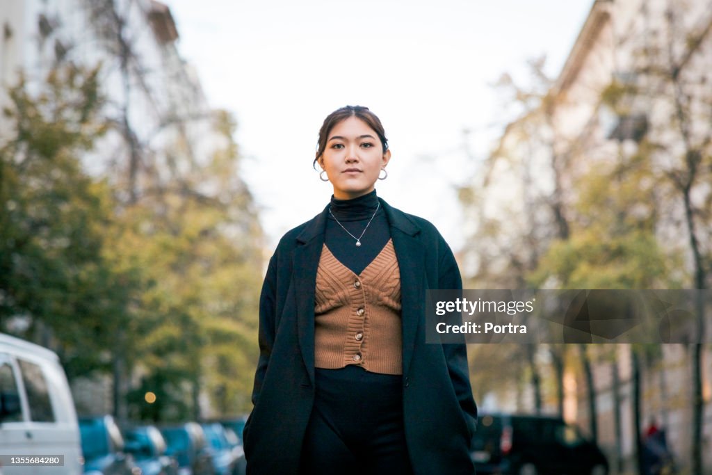 Portrait of a confident young woman standing on city street