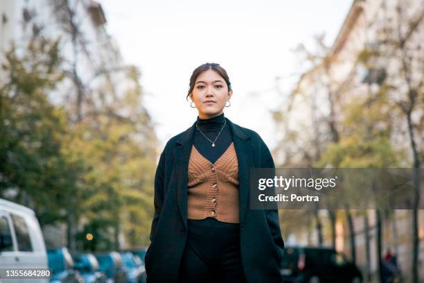 portrait of a confident young woman standing on city street - a fall from grace 個照片及圖片檔