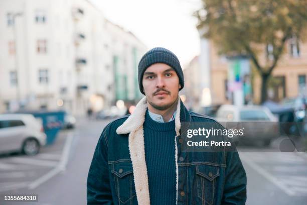 portrait of a young man standing on city street - suave stock pictures, royalty-free photos & images