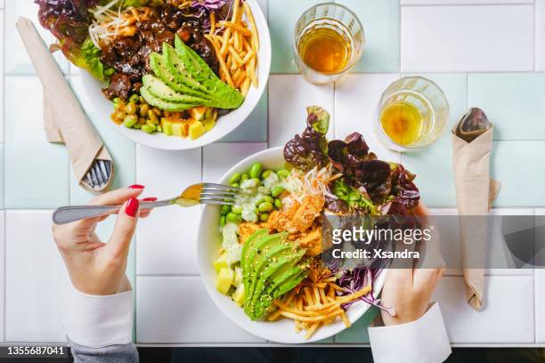 donna che mangia un'insalatiera vegana per il pranzo al ristorante - seitan foto e immagini stock