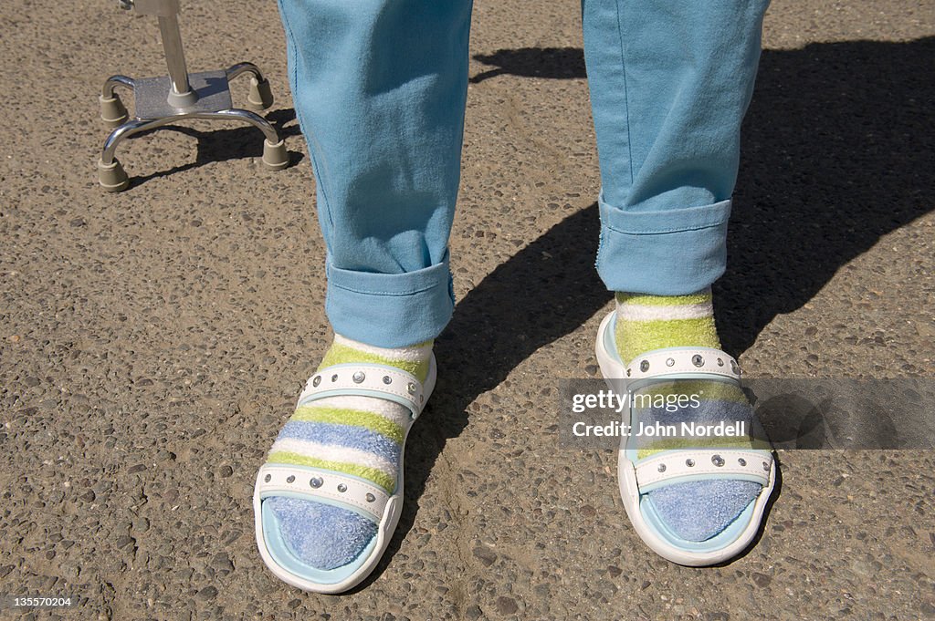 Old woman sporting bright pants, socks, and sandals