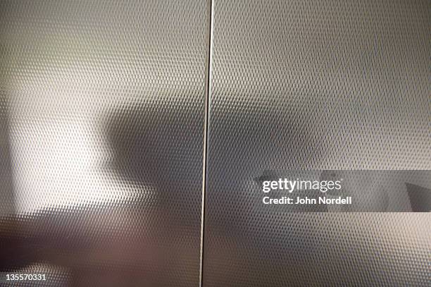 shadow of a 9 year old girl on the metal wall of a parking garage elevator - elevator doors stock-fotos und bilder