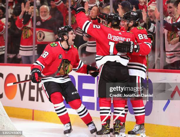 Brandon Hagel, Alex DeBrincat and Patrick Kane of the Chicago Blackhawks celebrate a win over the St. Louis Blues at the United Center on November...
