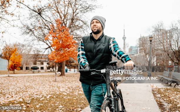 young man with prosthetic arm pushing a bike - disability awareness stock pictures, royalty-free photos & images