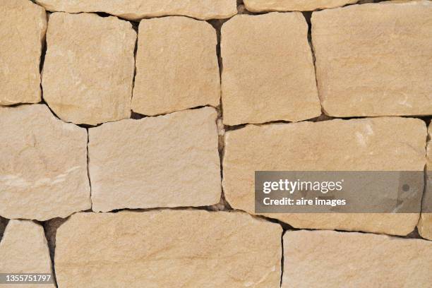 stone wall photography, close-up of abstract wall built with sand-colored stones. - arenito - fotografias e filmes do acervo