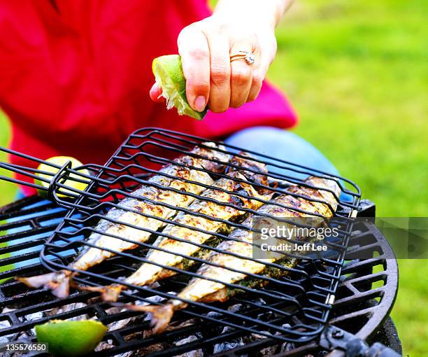 lime being squeezed over mackerel on barbecue - mackerel - fotografias e filmes do acervo