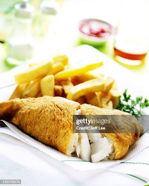 cooked cod and chips on kitchen paper - ausbackteig stock-fotos und bilder