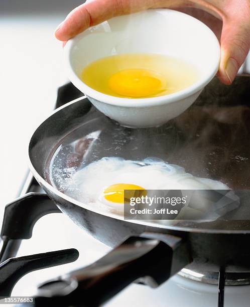 eggs being poached in frying pan - pochiert stock-fotos und bilder