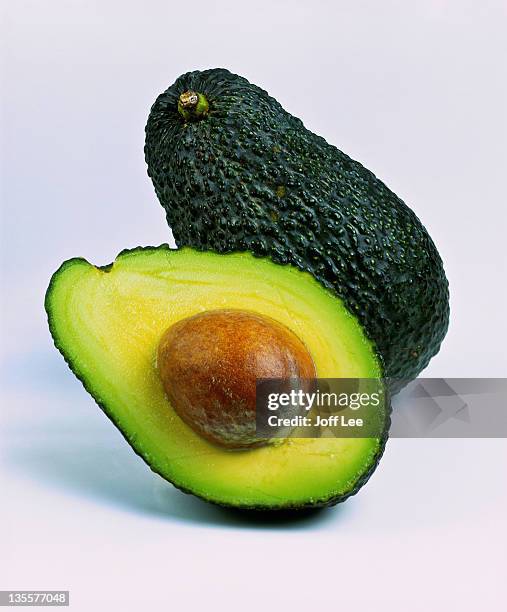 hass avocado sliced in half wih stone exposed - avocado stock pictures, royalty-free photos & images