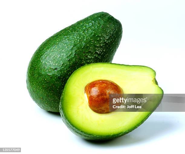 fuerte avocado cut in half with stone exposed - avocado stock-fotos und bilder