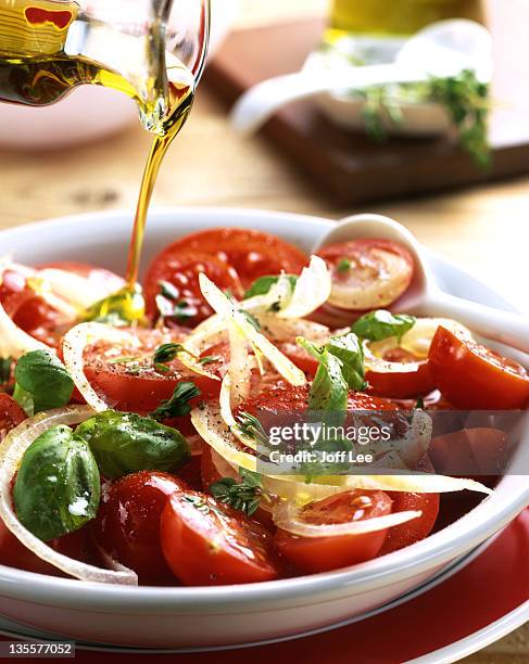 olive oil pouring over tomato and basil salad - olive oil stock pictures, royalty-free photos & images