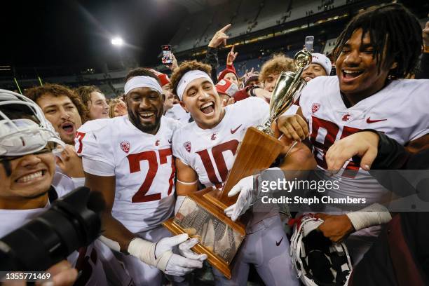 Ron Stone Jr. #10 of the Washington State Cougars and his teammates celebrate with the Apple Cup after defeating the Washington Huskies 40-13 at...