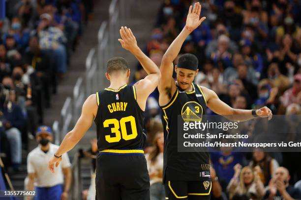 Golden State Warriors guard Jordan Poole high-fives teammate Stephen Curry during the second quarter of their NBA basketball game against Portland...