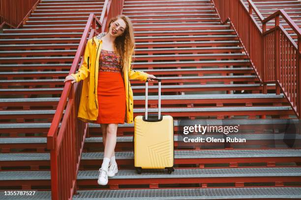 young woman sticking out tongue with yellow suitcase. - yellow suitcase stock pictures, royalty-free photos & images