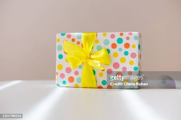 white gift box in a colored pattern with a yellow bow. - birthday present stock-fotos und bilder