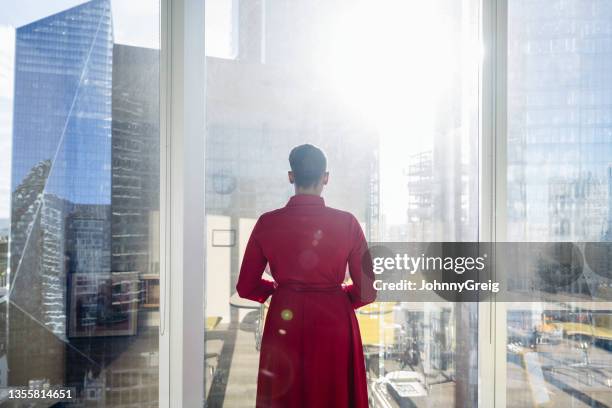 porträt einer kontemplativen schwarzen geschäftsfrau am fenster - red dress stock-fotos und bilder