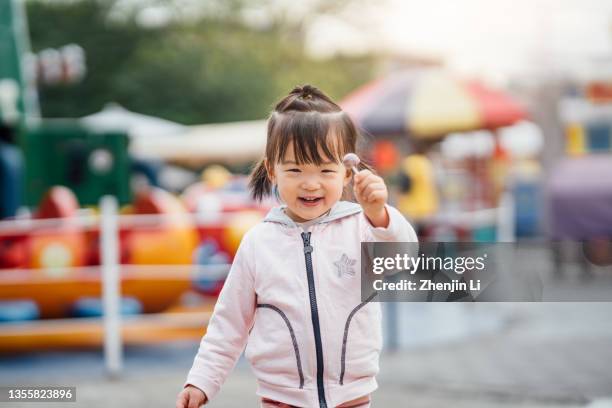 3 years girl holding lollipop in children park joyfully - 2 3 years one girl only ストックフォトと画像