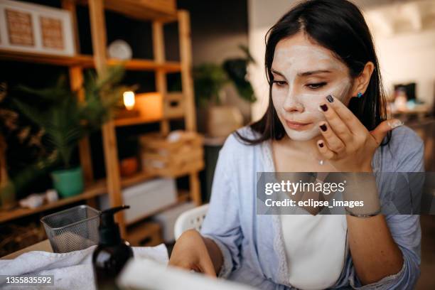 young woman applying facial mask. - woman facial expression stock pictures, royalty-free photos & images