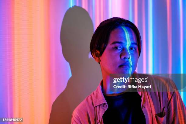 young man illuminated by neon lights - indonesian faces stock pictures, royalty-free photos & images