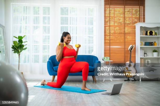 woman overweight watching sports training online on laptop - home workout foto e immagini stock