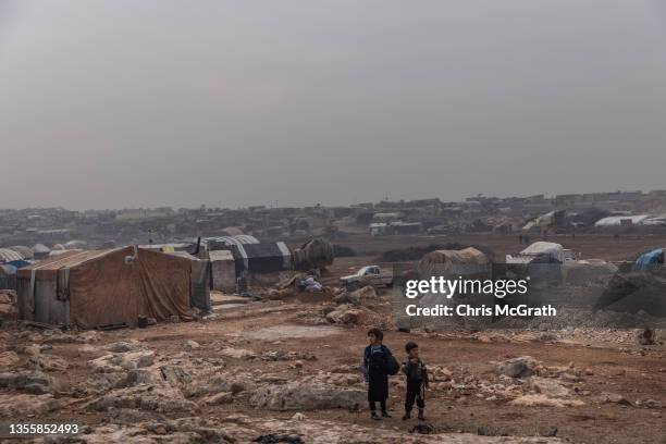 Displaced Syrian children are seen in front of tents at an informal displaced persons camp on the outskirts of Idlib, on November 26, 2021 in Sarmada...