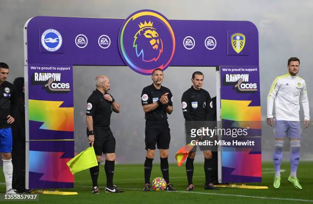Referee, Craig Pawson stands with Assistant's Lee Betts and Richard West in front of the Rainbow Laces handshake board, as clubs show support for the...