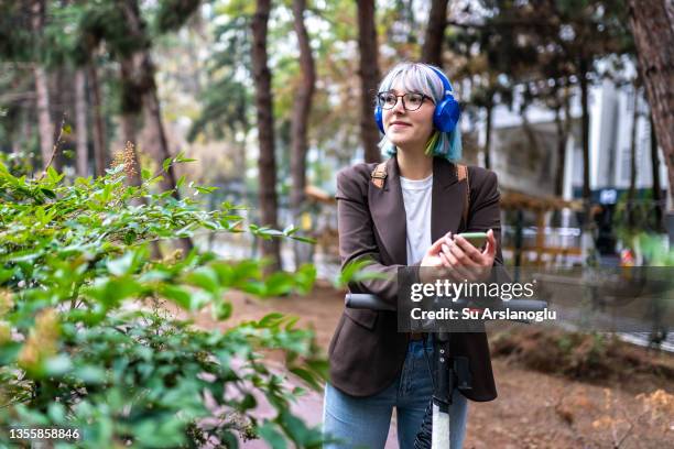 young woman with colored hair goes to work by electric scooter - bike sharing stock pictures, royalty-free photos & images