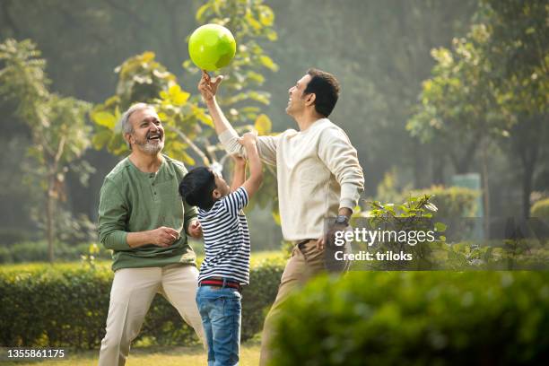 three generation family playing with ball at park - grandparents raising grandchildren stock pictures, royalty-free photos & images