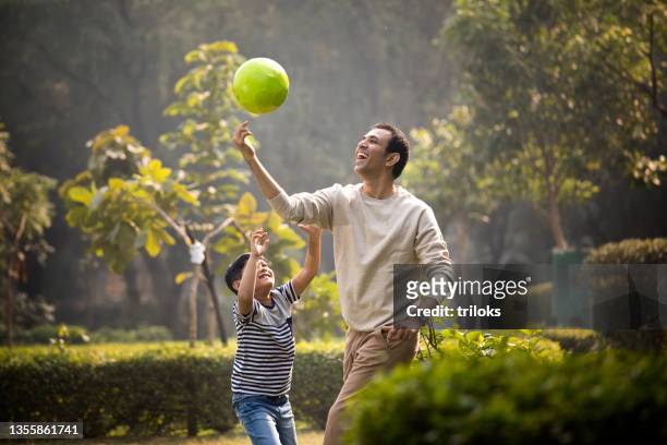 father and son having fun while playing with ball at park - playing stock pictures, royalty-free photos & images