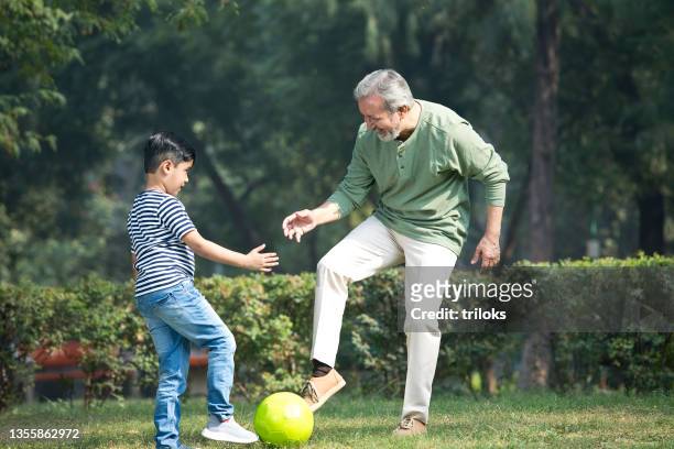 senior man playing with grandson at park - playing stock pictures, royalty-free photos & images
