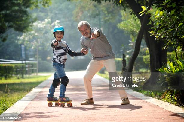 avô ajudando seu neto patinando no parque - indian grandparents - fotografias e filmes do acervo