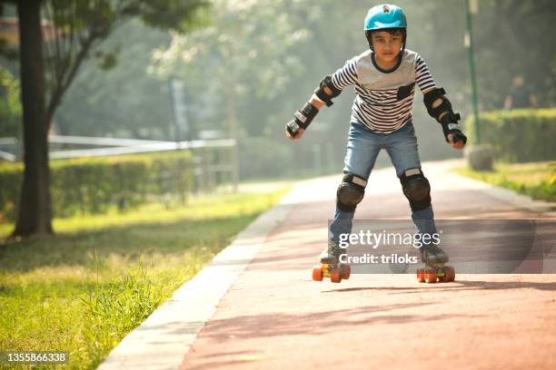 boy learning roller skating at park - kneepad stock pictures, royalty-free photos & images