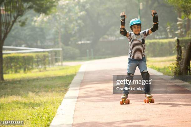 junge lernt rollschuhlaufen im park - knieschützer stock-fotos und bilder