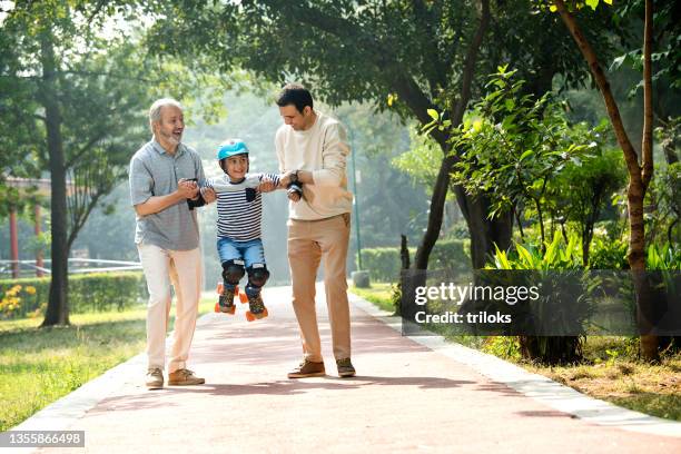 boy learning roller skating with father and grandfather at park - kneepad stock pictures, royalty-free photos & images