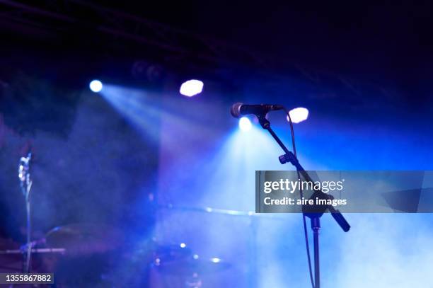 rear view low angle view of a microphone and spotlights on stage at a live concert with musical instruments background - popular music concert stock-fotos und bilder