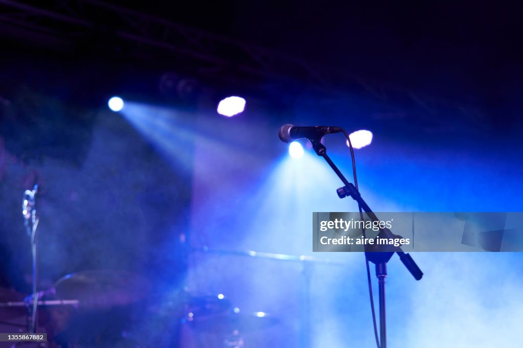 Rear view low angle view of a microphone and spotlights on stage at a live concert with musical instruments background