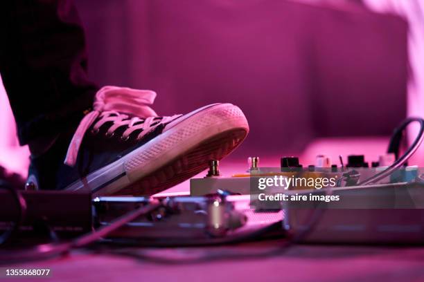 close-up of low section of a bass guitarist using on his effects pedals while practicing for live concert - amplificador fotografías e imágenes de stock