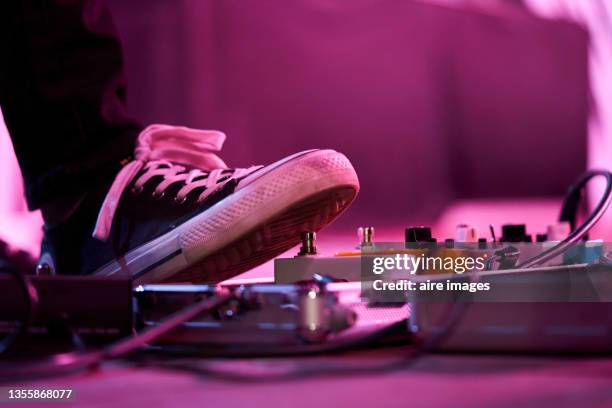 close-up of low section of a bass guitarist using on his effects pedals while practicing for live concert - versterker stockfoto's en -beelden