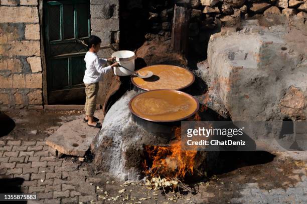 el niño que hace melaza en calderas encendidas en un fuego de chimenea - stew pot fotografías e imágenes de stock
