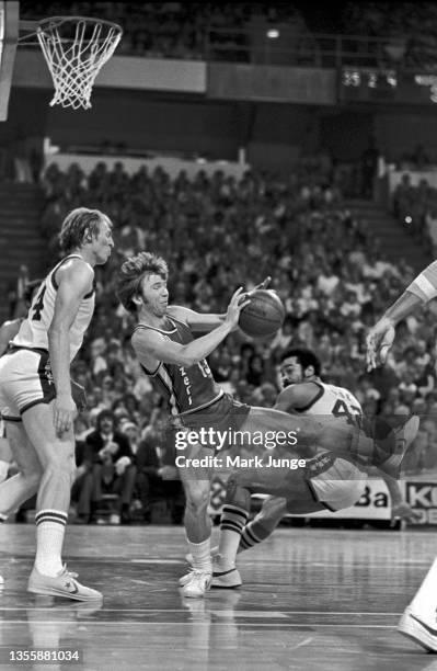 Portland Trail Blazers point guard Dave Twardzik falls backward under the basket between Denver Nuggets center Dan Issel and Willie Wise during an...