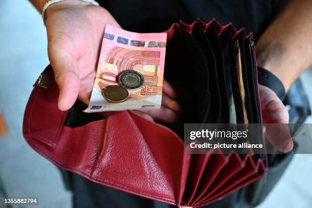 June 2023, Bavaria, Munich: A waiter at a restaurant is holding a wallet in his hand while holding money in the other hand. Photo: Felix Hörhager/dpa