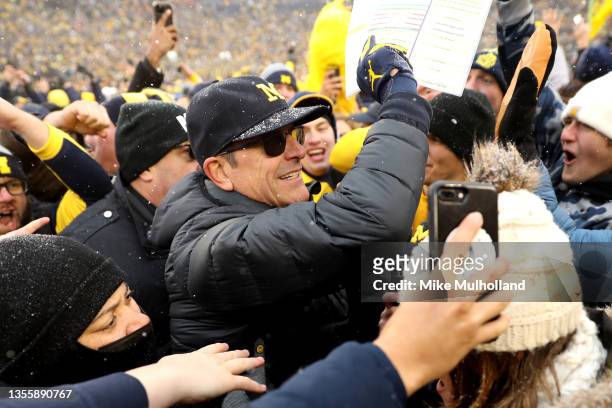 Head Coach Jim Harbaugh of the Michigan Wolverines celebrates with fans after defeating the Ohio State Buckeyes at Michigan Stadium on November 27,...