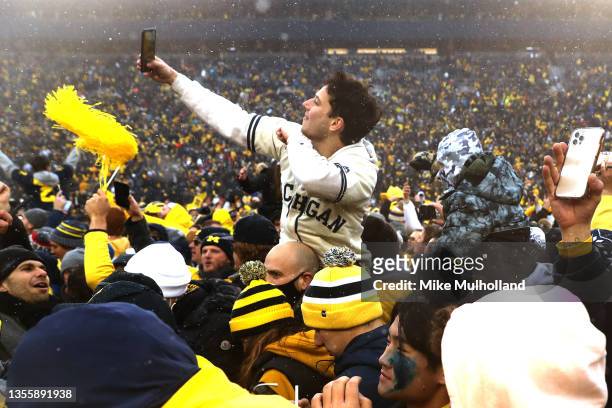 Michigan Wolverines fans celebrate on the field after the Wolverines victory over the Ohio State Buckeyes at Michigan Stadium on November 27, 2021 in...