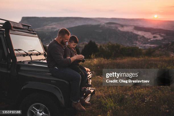 father teaching son to photograph on old film photo camera outdoors at sunset - car nature ストックフォトと画像