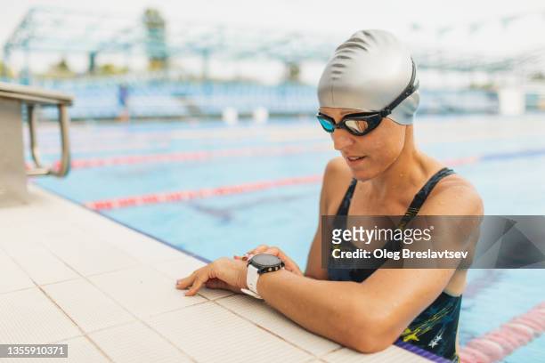triathlete woman checking results of swimming on smartwatches. fitness gadgets in professional sport - exercise watch stock-fotos und bilder