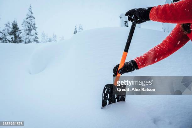 close up of a backcountry skier using an avalanche shovel to dig a snow pit - avalancha stock-fotos und bilder