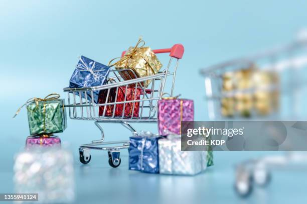 black friday sale and online shopping concepts, mini shopping cart carrying with multi colored gift box on blue isolated background. - black friday shopping event fotografías e imágenes de stock