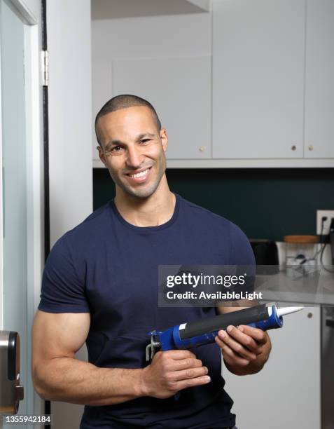 caulking gun turkish man smiles at camera vertical - caulking stockfoto's en -beelden